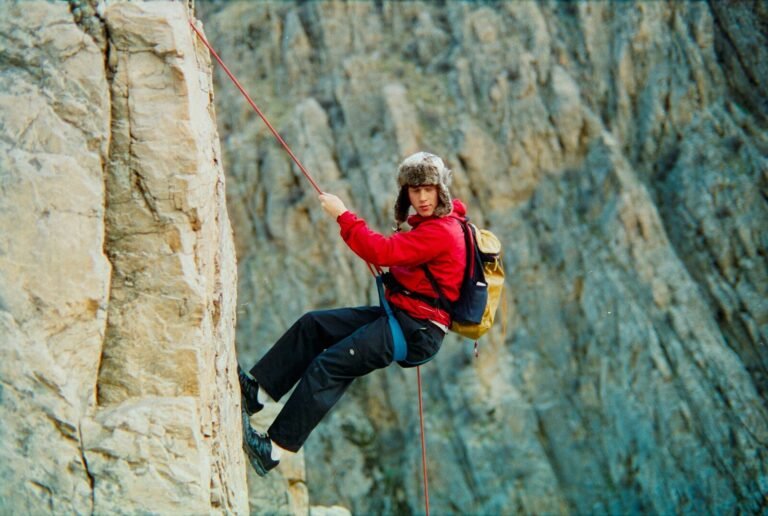 Woman rappels down a rocky cliff face